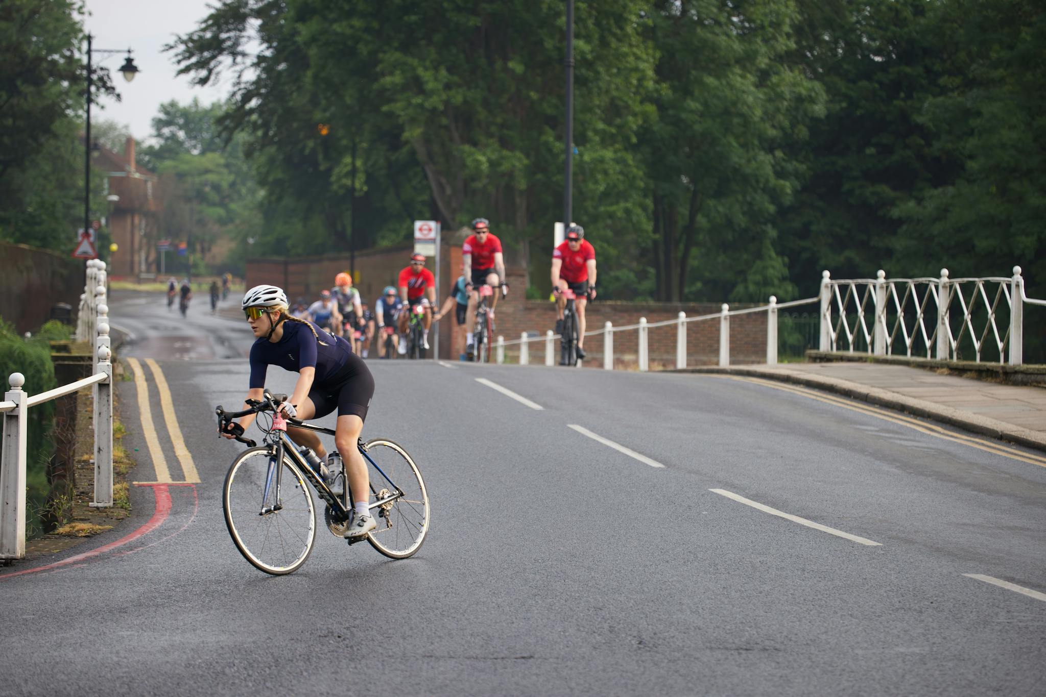 Group of cyclists engaged in a charity bike race on an urban road surrounded by greenery.